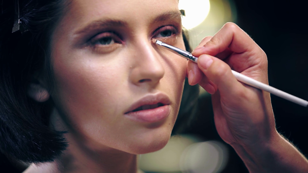 vista de perto do artista de maquiagem aplicando sombra de olho na pálpebra inferior do modelo com escova cosmética
 - Filmagem, Vídeo