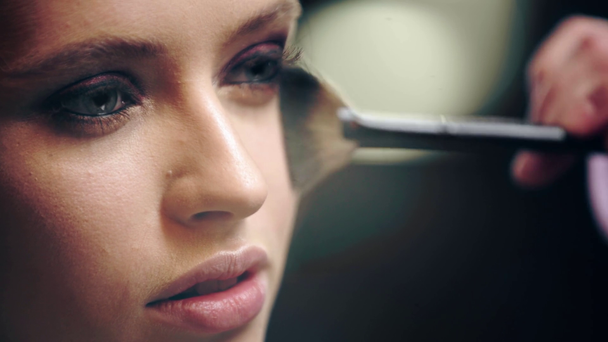 bliska makijaż malarza powdering twarz modelu z pędzlem kosmetycznym - Materiał filmowy, wideo
