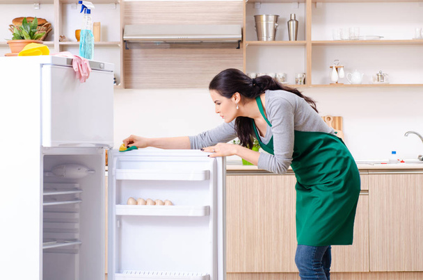 Fiatal nő takarítás hűtőszekrény higiéniai koncepció  - Fotó, kép
