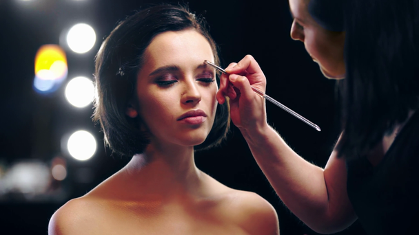 makeup artist applying eyebrow shades on model eyebrow with cosmetic brush - Metraje, vídeo
