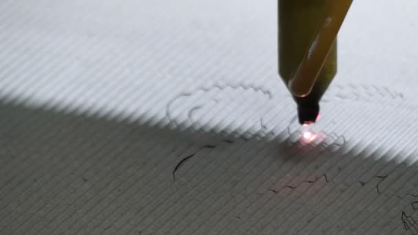 O desenho é feito com um dispositivo laser em uma placa branca ondulada em uma oficina
 - Filmagem, Vídeo