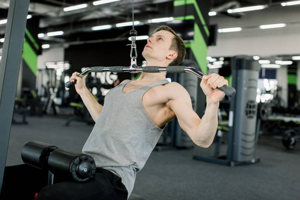 Fitness Caucasian man working out shoulder pull down at gym. Man strength training using lat pulldown machine. - Foto, Imagem