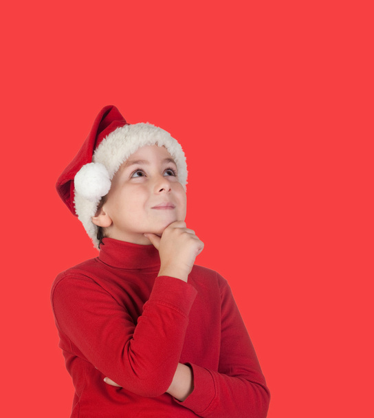 Niño pensativo con pelo rubio y sombrero de Navidad
 - Foto, Imagen