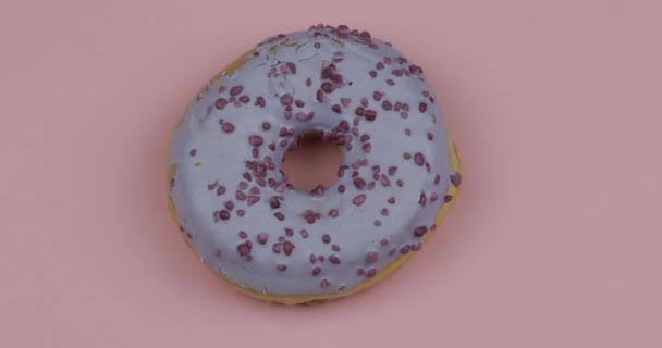 Süßer Donut auf rosa Hintergrund. Ansicht von oben. Leckerer, frisch bestreuter Donut - Filmmaterial, Video