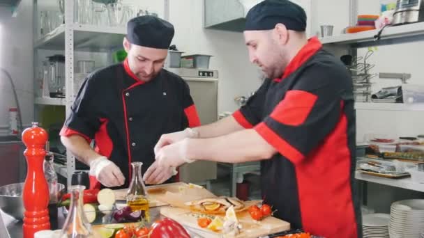 Cocina del restaurante. Dos hombres chefs trabajando en servir plato de pescado en la tabla de cortar
 - Metraje, vídeo