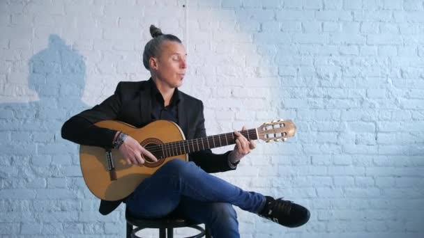 guitar player playing  flamenco music on an acoustic guitar against a white brick wall - Imágenes, Vídeo