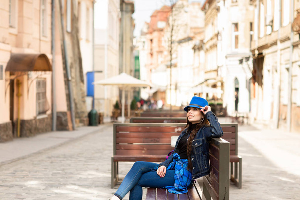 Μια νεαρή γυναίκα κάθεται σε ένα παγκάκι στο παλιό δρόμο, και ξεκουράζεται. Λβιβ, Ουκρανία - Φωτογραφία, εικόνα