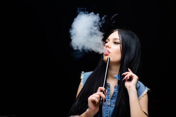 hookah bar. Electronic cigarette. Bad habit. Woman vapor. unhealthy addiction. Tabacco drug. exhale smoke on black background. sexy woman smoking cigar. copy space. Above the Influence - 写真・画像