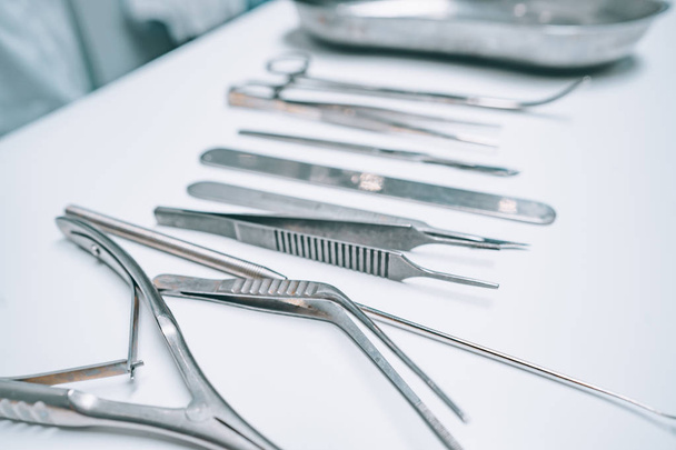 Několik chirurgických nástrojů leží na bílém stole - Fotografie, Obrázek