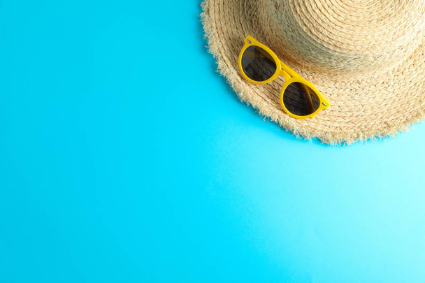 Straw hat and sunglasses on color background, space for text - Foto, afbeelding