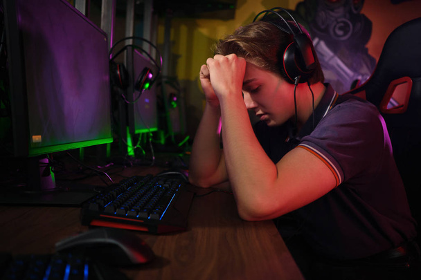 Professional young caucasian gamer playing online on his PC. He upset because of losing the game - Фото, изображение