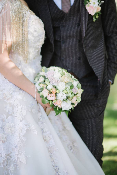 Bride in a wedding dress holding a wedding bouquet in her hands close-up - Foto, imagen