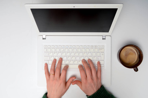 Hands on laptop computer keyboard at white desk. High angle over - Fotografie, Obrázek