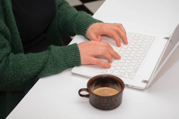 eine Frau mit einem Laptop sitzt an einem weißen Schreibtisch - Foto, Bild