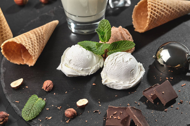 Изысканные сливочное и шоколадное мороженое подается на каменной доске на черном фоне
. - Фото, изображение