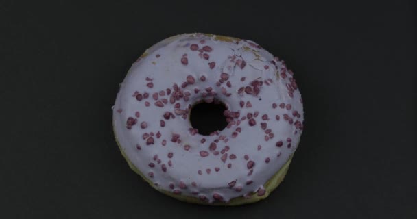 Sweet donut rotating on black background. Top view. Tasty, fresh sprinkled donut - Footage, Video