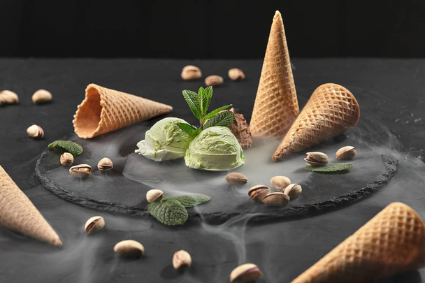 Chocolate gourmet y helado de pistacho servido sobre una pizarra de piedra sobre un fondo negro
. - Foto, Imagen