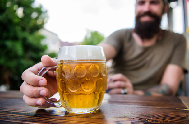 Creative young brewer. Craft beer is young, urban and fashionable. Distinct beer culture. Mug cold fresh beer on table close up. Man sit cafe terrace enjoying beer defocused. Alcohol and bar concept - Foto, Imagem