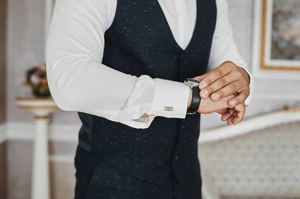タキシードとカフリンクス付きシャツを着たハンサムなビジネスマンの手に高級腕時計を近い - 写真・画像