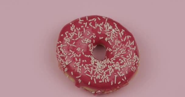 Zoete donut draaiend op roze achtergrond. Bovenaanzicht. Lekkere, verse besprenkelde donut - Video