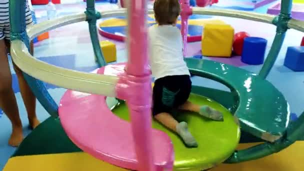 4k video of toddler boy riding on colorful carousel at amusement park in shopping mall - Footage, Video