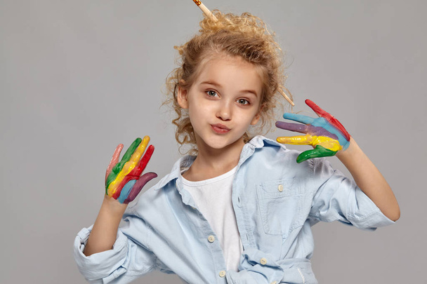 Beautiful little girl with a painted fingers is posing on a gray background. - Foto, imagen