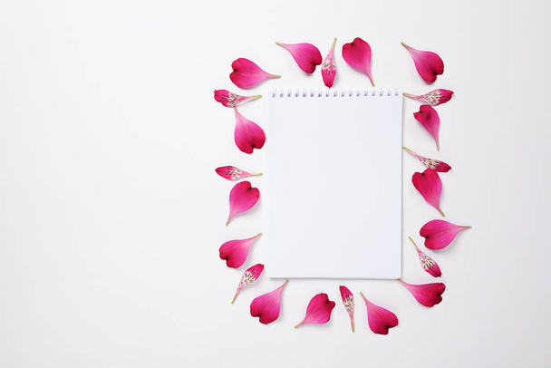 The notebook surrounded by pink petals of Alstroemeria flowers and text space - Foto, Bild