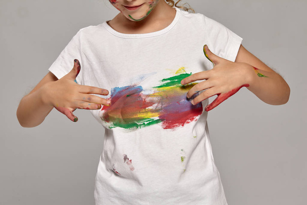 Mooi klein meisje met een geschilderde vingers poseren op een grijze achtergrond. - Foto, afbeelding