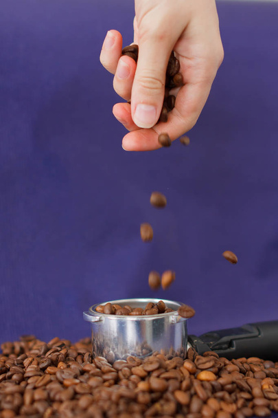 Γυναικείο χέρι που ρίχνει τους κόκκους καφέ στο καφέ-φόντο. - Φωτογραφία, εικόνα