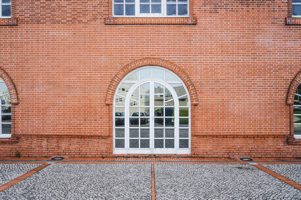 Pared de ladrillo rojo con hermosa ventana de arco blanco. Detalle del edificio con arquitectura típica europea
. - Foto, Imagen