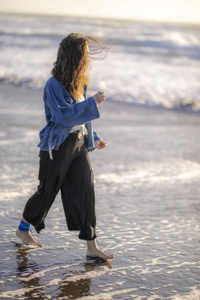 Beautiful young girl walking along the beach  - 写真・画像