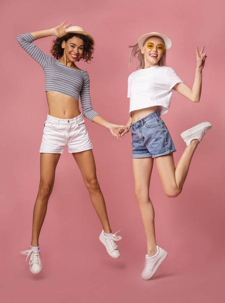 Симпатичные девушки, прыгающие на розовом студийном фоне
 - Фото, изображение