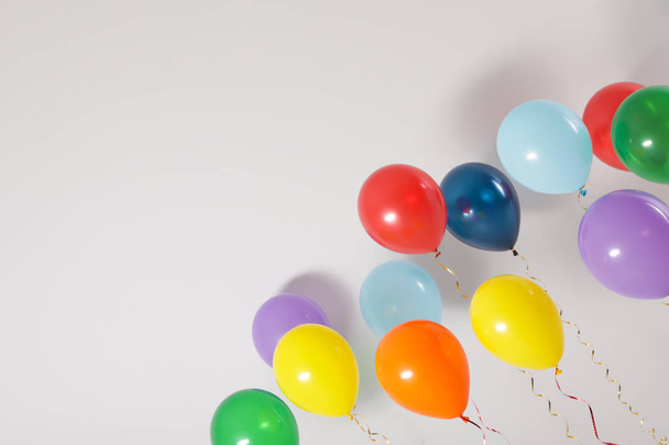 Different bright balloons on light background, space for text. Celebration time - Foto, afbeelding