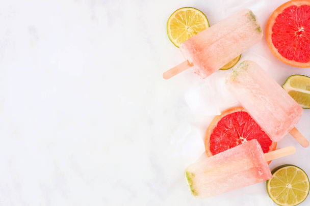 Sparkling lime and grapefruit popsicles. Top view, side border on a marble background with copy space. - Photo, Image