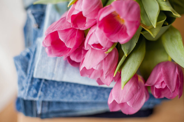 Na hromadě džínů se povalí kytice tulipány. Oblečení. - Fotografie, Obrázek
