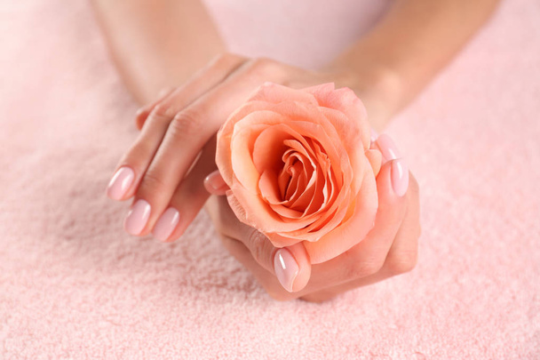 Closeup view of beautiful female hands with rose on towel. Spa treatment - Фото, зображення