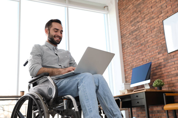 Young man in wheelchair using laptop at office - Foto, Imagem