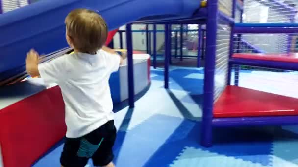 4k video of little toddler boy climbing and playing on soft playground at amusement park. Active children having fun - Footage, Video