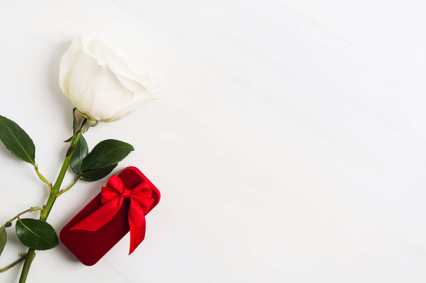 Червона коробка для ювелірних прикрас з червоним цибулею і білою троянди на білому текстурованою фону. День Святого Валентина або весілля концепцію. Знак любові. Копіювати пробіл - Фото, зображення