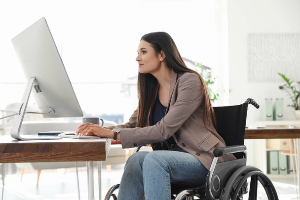 Young woman in wheelchair using computer at workplace - Φωτογραφία, εικόνα