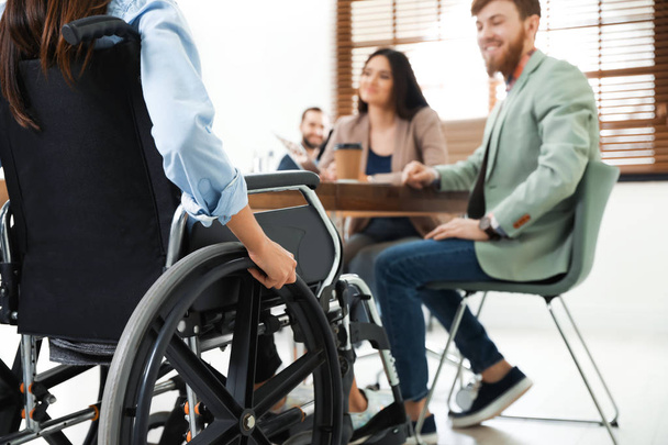 Young woman in wheelchair with colleagues at office, closeup - Fotografie, Obrázek