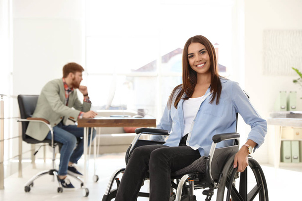 Young woman in wheelchair with colleague at office - Fotografie, Obrázek