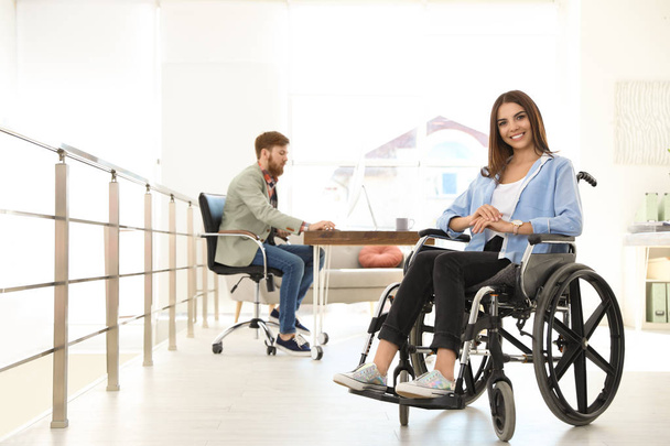Young woman in wheelchair with colleague at office - Fotoğraf, Görsel