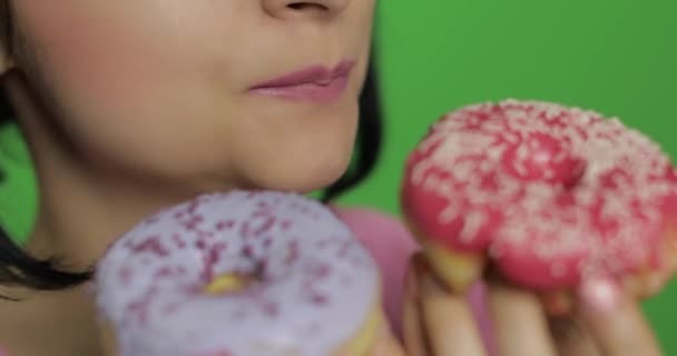 Gelukkig mooi jong meisje poseren en likken kleurrijke bespelde zoete donut - Video