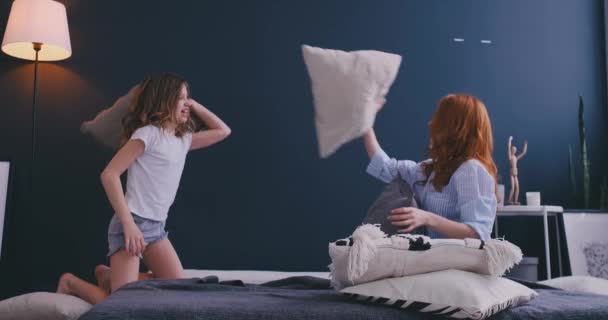Щаслива мама старша сестра і дівчинка насолоджуються смішною постільною бійкою на ліжку, няня мати з маленькою донькою розважається разом у спальні, весела сім'я грає сміючись разом вранці
 - Кадри, відео