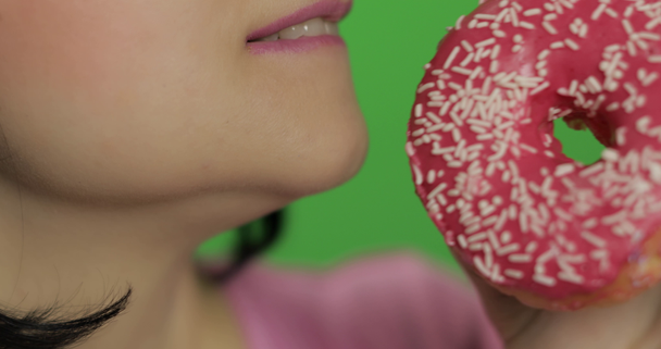 Feliz hermosa joven posando y lamiendo colorido espolvoreado donut dulce
 - Metraje, vídeo