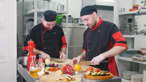 Étterem konyha. Két férfi dolgozik szolgáló ételek vágás citrom és zöld - Felvétel, videó