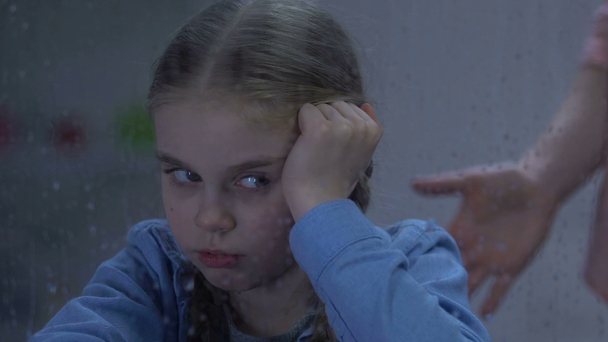 雨の窓の近くに座っている小さな泣いている女の子に叫ぶ女性、子供の屈辱 - 映像、動画