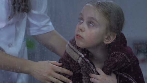 Enfermeira cobrindo pequena menina triste com xadrez quente, criança faltando em casa no hospital
 - Filmagem, Vídeo