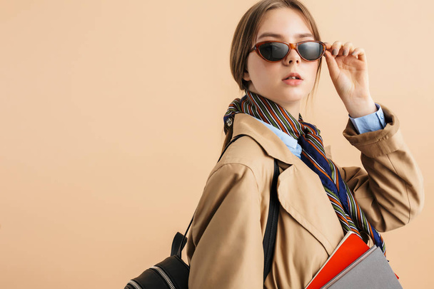 Young attractive lady in trench coat and sunglasses with backpac - Foto, imagen